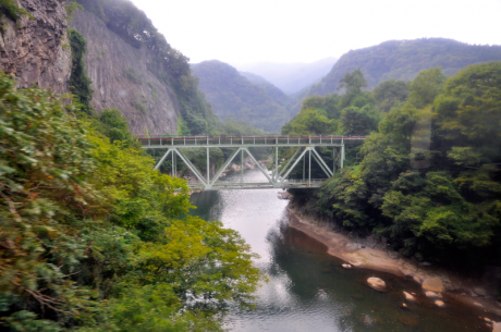 上り線の車窓から見た下り線の鉄橋。峡谷の先にある写真中央の山の下に児子岩がある。