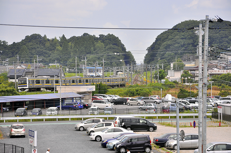 外房線下り線ホームから北側を遠望して捕らえた東金線を走る209系電車。直線になっている辺りが旧大網駅跡。