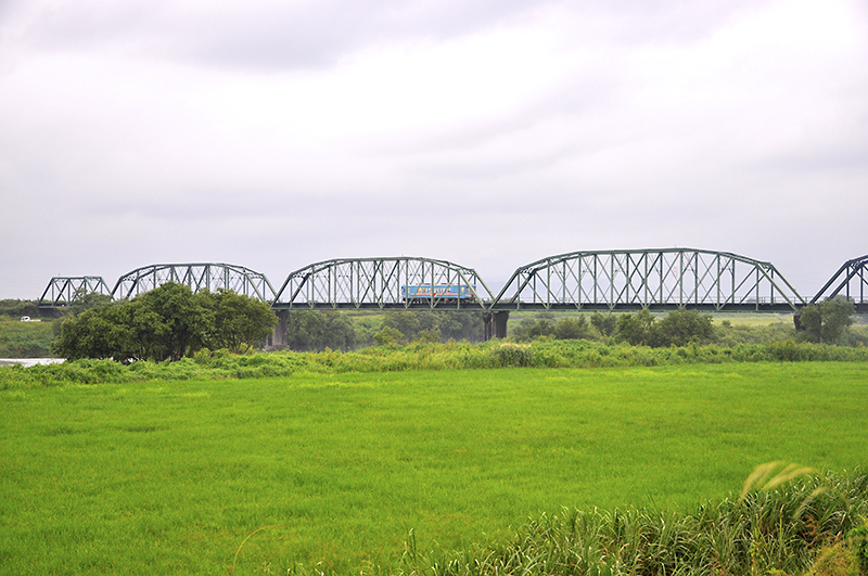 樽見鉄道の揖斐川橋梁を、横屋側岸から眺めたところ。上写真のYR-880形とほぼ同じ車格の18m車ハイモ295-516形で鉄橋の大きさを比較すると、製造年代による大きさの違いに当時の技術の進歩が窺える。ちなみに一番左の橋桁は1916年(大正5年)川崎造船所製で、それ以外の橋桁が1900年アメリカ合衆国Aアンドp・ロバーツ製下路曲弦プラットトラス。 