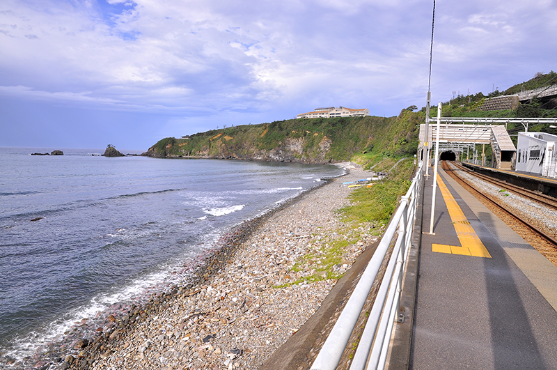 下り線プラットホーム直江津駅寄りから新潟駅方向を見たところ。防潮堤の上にプラットホームが築かれ、海が真下に迫る。