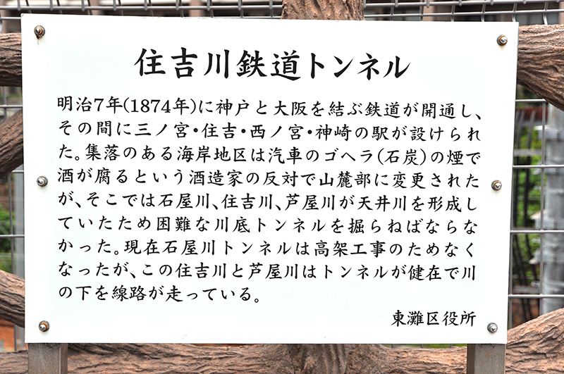 住吉川跨線道路橋の南西側袂に立てられている「住吉川鉄道トンネル」の説明板。官設鉄道の線路が山側のルートを選んだ経緯が書かれている。