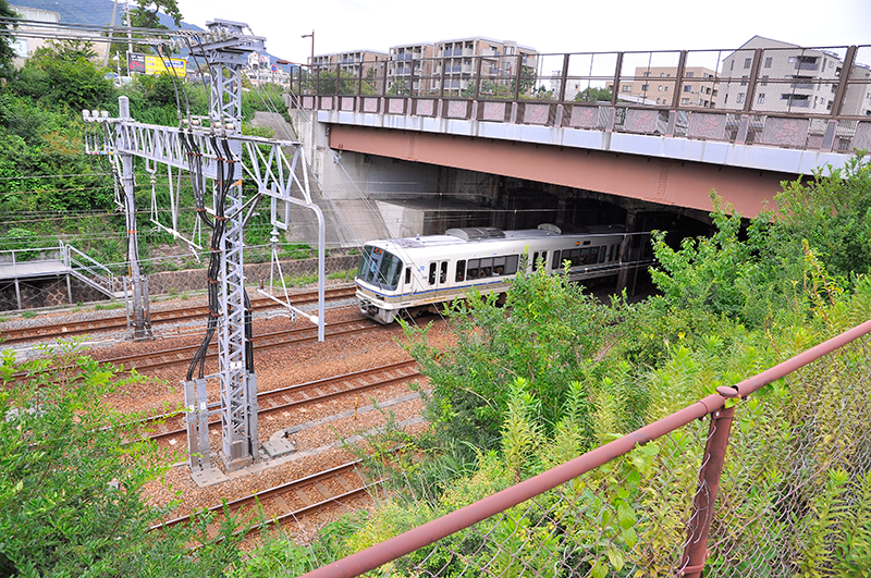 芦屋川水底トンネルの甲南山手寄りからの眺め。エンジ色の跨線道路橋の向こうに上写真画面左や中央の建物が垣間見えるので、位置的に奥のコンクリート構造物の上が河川であることが解るだろう。