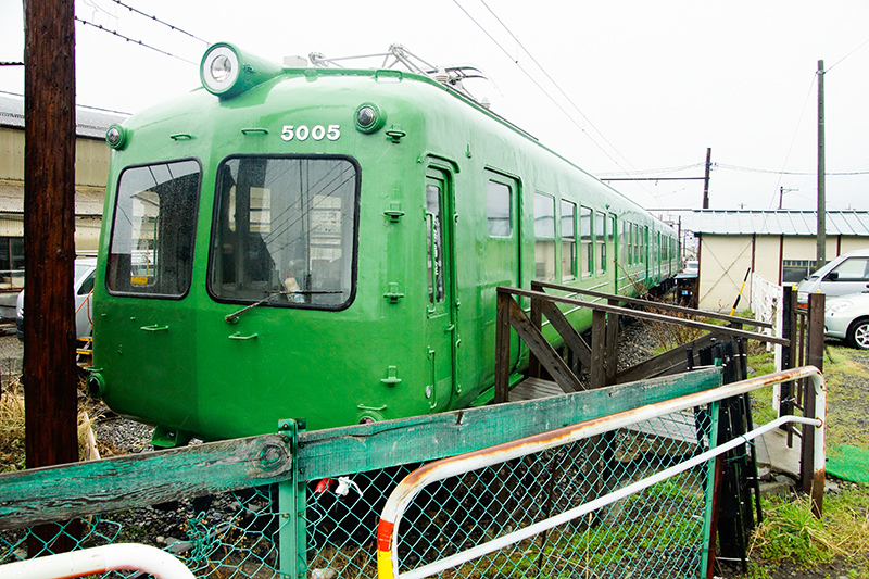 新島々寄りのモハ5005。新村駅前の道路を右手に進み踏切を渡った地点からの眺めで、普段の日の車庫の立ち入りはできないが、道路脇のスペースからでも、このくらいまで近寄ることができる。