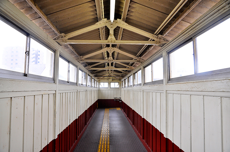 階段を上がって橋梁部内を駅舎側からプラットホーム方を眺めたところ。梁や垂木などが鋳鉄のLアングルで組まれているのが見て取れる。