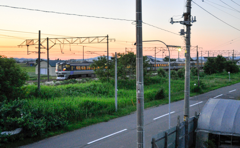 785系使用の2040Mスーパーカムイ40号が19時26分頃通過。続いて写真の785系使用の2033Mスーパーカムイ33号が19時30分頃通過したのち、夏とはいえそろそろ夜の帳が降りてきたので、ひとっ風呂浴びに。その後部屋に戻り、あとは窓ガラス越しに、先ほど買ってきた酒と肴でトレインビューのお一人様宴会。列車通過のジョイント音を聴きながらの心地良い夜を過ごすことができた。