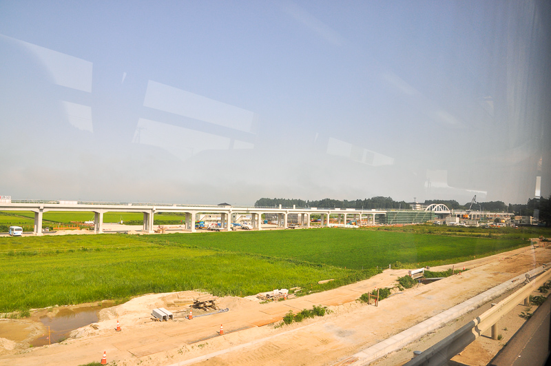 2015年8月3日に国道6号から撮影した建設中の坂元駅付近。左側が岩沼方で、右側が駒ヶ嶺方になる。そして、右にあるアーチが上写真の下路式アーチローゼ橋で、その右に坂元駅がある。
