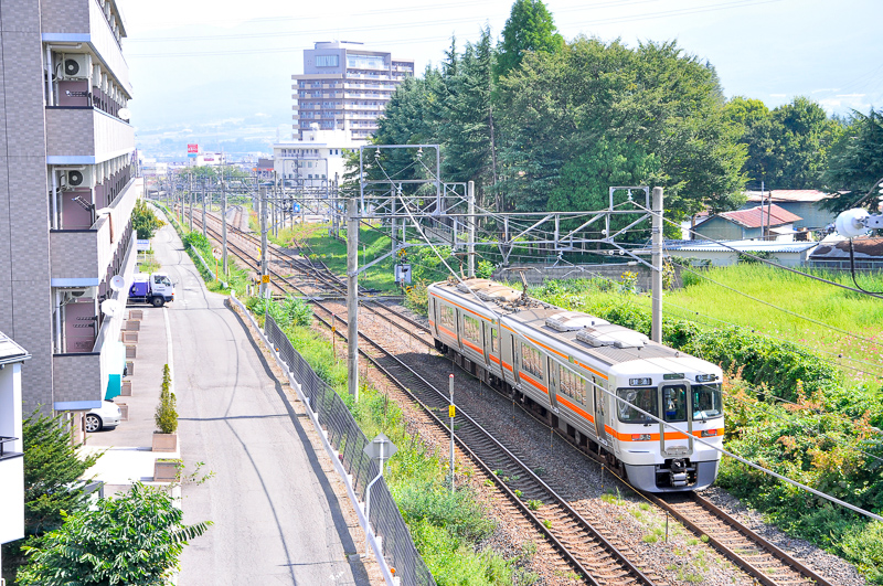 短絡線(元・中央西線)の現・中央西線側の分岐付近を、その南側にある跨線橋上から北向きに眺めたところ。手前の分岐器が短絡線ので、奥は塩尻駅4Tに名古屋方から入る線への分岐器。313系使用の列車は実は後追いで、普通 松本行。写真のさらに手前にある名古屋寄りの片渡り線でこの線に入り、この後にまさにその奥の分岐器を右に入って4Tに行く。