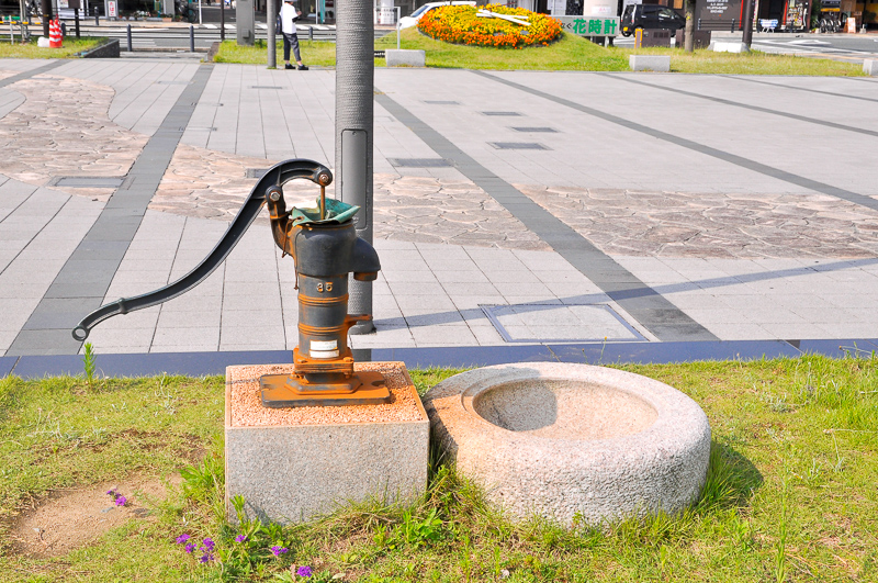 福知山駅北口側の駅前広場にはオブジェやモニュメントは数点あるが、鉄道系アートは見あたらない。そんな中、井戸ポンプが曰くありげに展示されていた。謎のモニュメントだ。