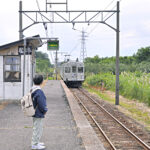 林檎畑の中にある電化地方私鉄の単線棒線無人中間駅を眺める